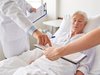 Patiente âgée, allongée dans un lit d'hôpital, conseillée par du personnel de santé.