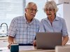 Un couple de personnes âgées s'informe ensemble à la maison sur l'ordinateur.