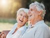 Couple souriant et en bonne santé assis en riant sur un banc.