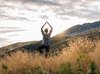 Une jeune femme pratique le yoga dans une prairie au cœur des montagnes.